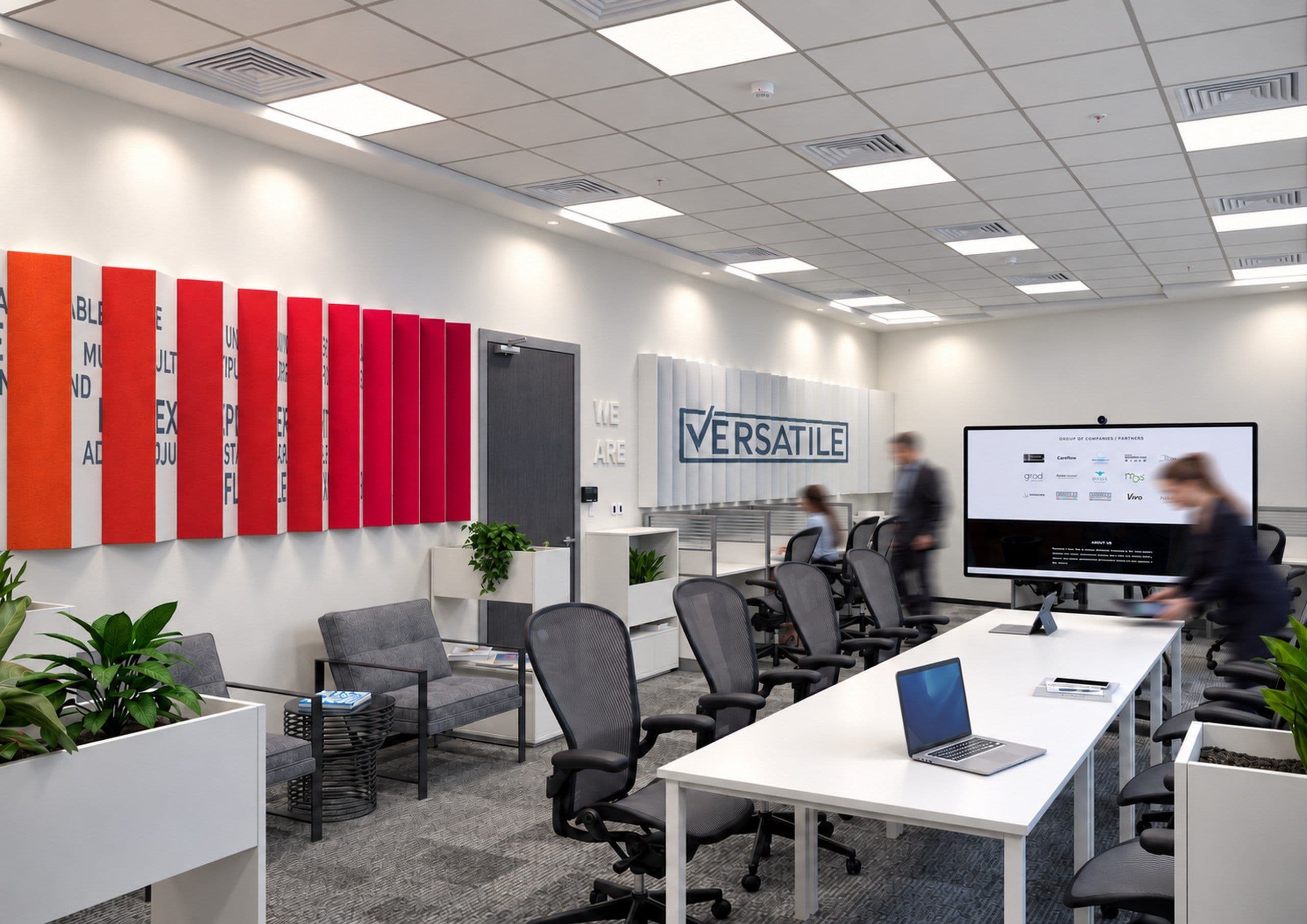 Meeting area with a red acoustic panel wall, a screen and a long desk